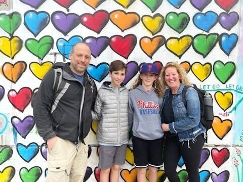 Family standing in front of heart-patterned banner