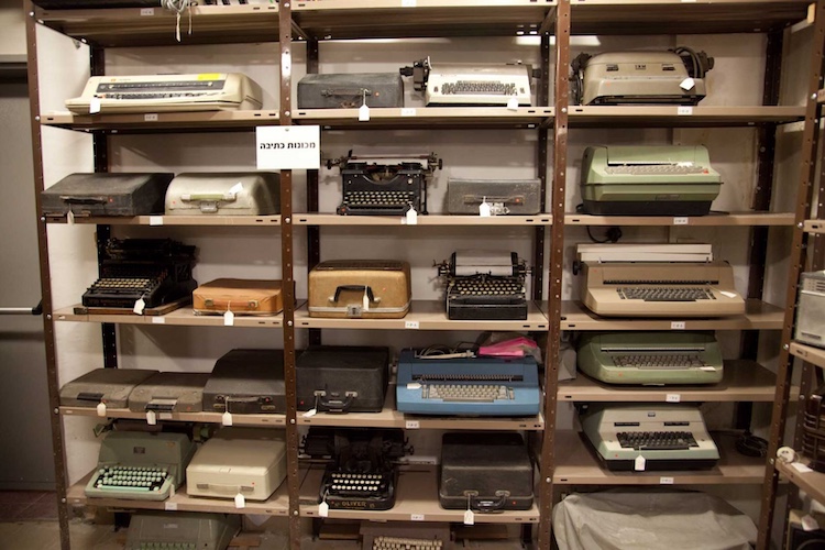 Rows of antique typewriters on metal shelves.