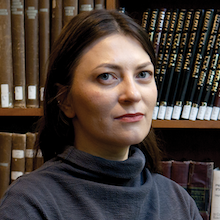 Headshot photograph of white woman seated in front of bookcase.