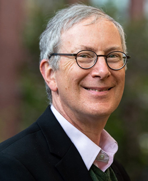 headshot of man wearing round glasses