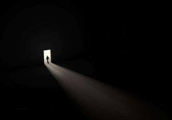 silhouette of man in tiny threshold surrounded by darkness