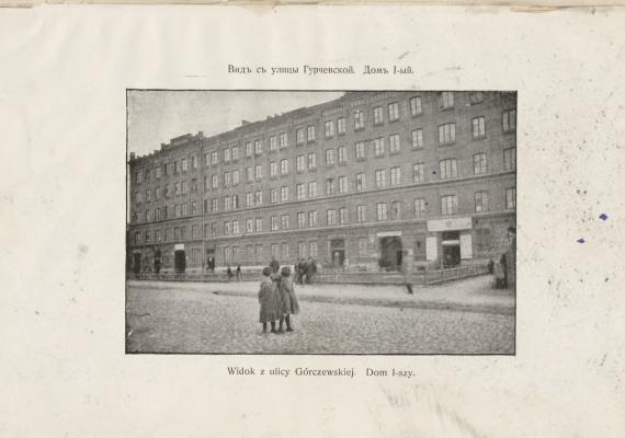 black and white photograph of the first apartment block constructed in Warsaw with people in front.