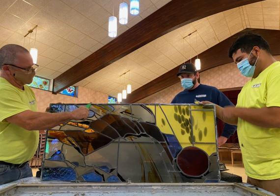 men disassembling stained glass window