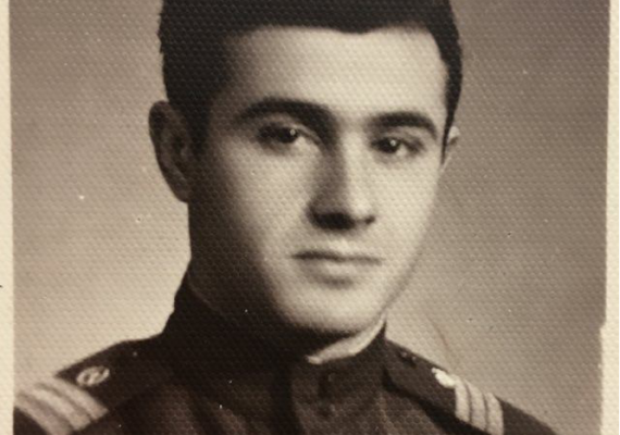 black and white photograph of man in military uniform, seated for a portrait and looking at the viewer