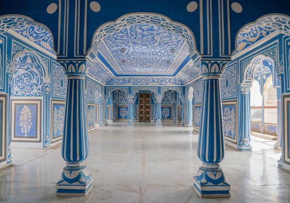 Ornate blue and white paintings cover palace interior walls, ceiling, and pillars.