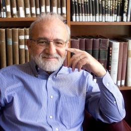 Bearded man seated in front of bookcase