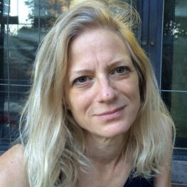 Woman sitting outdoors looks up at viewer