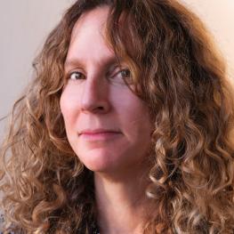 Photograph of woman with curly hair partially covering her face.