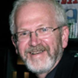 Snapshot photograph of bearded man turning and smiling at the viewer.
