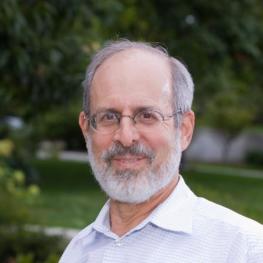 Headshot photograph of man standing outside.